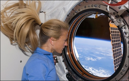 Astronaut Karen Nyberg, STS-124 mission specialist, looks through a window in the newly installed Kibo laboratory of the International Space Station while Space Shuttle Discovery is docked with the station on June 10th, 2008